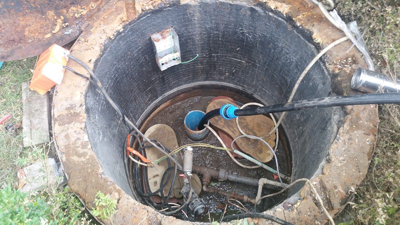 Privit de sus, un puț cu inele de beton, cu pompa submersibilă coborâtă și conducta de refulare, august 2016