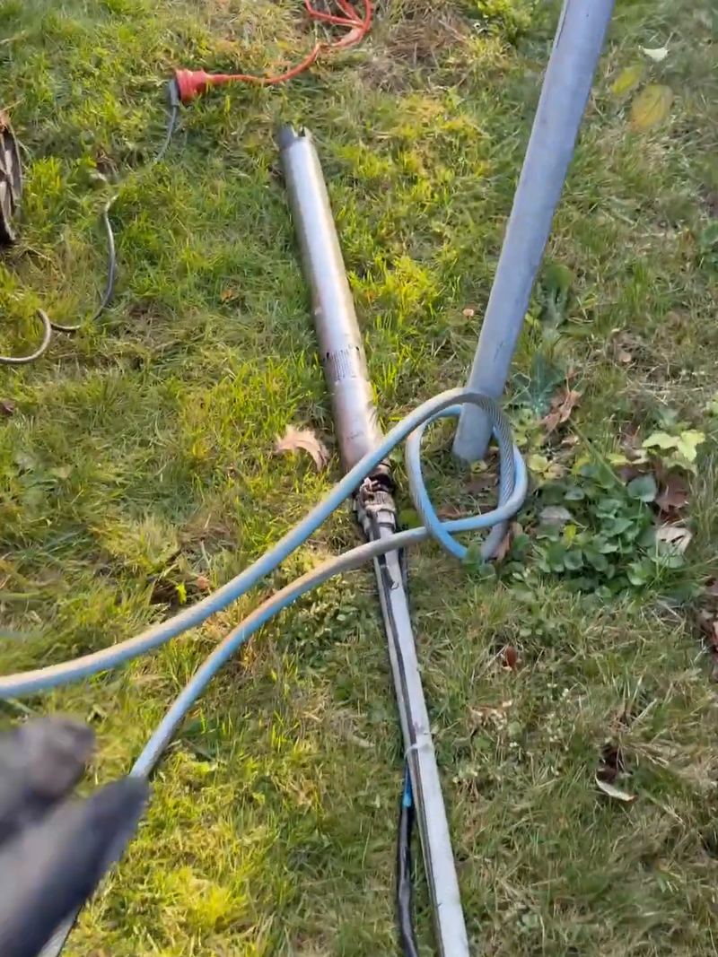 Țevile de air-lift scoase din puț, pe iarbă, cu furtunul de aer al compresorului, la o denisipare în Ciolpani