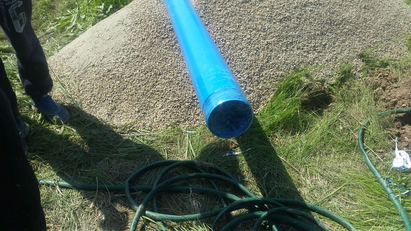 Țeavă de PVC albastră cu fante, capac la capăt, așezată lângă o grămadă de pietriș de filtrare și furtunuri verzi, aprilie 2018, arhiva firmei